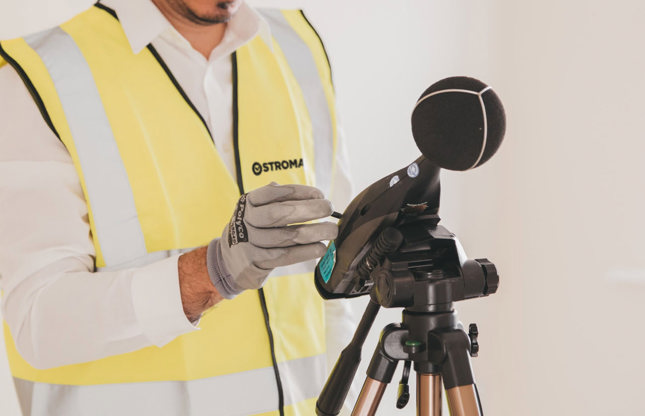 A Stroma technician adjusting a sound level meter on a tripod